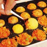 『ミニミニオムライス』《調理ポイント》卵が固まってきたら、いよいよ返すタイミング！ 小さめのスプーンをぐいっと入れ、すくうようにすると返しやすい。ひっつきにくいようプレートにバターを多めに塗っておくのもキレイに返すコツ