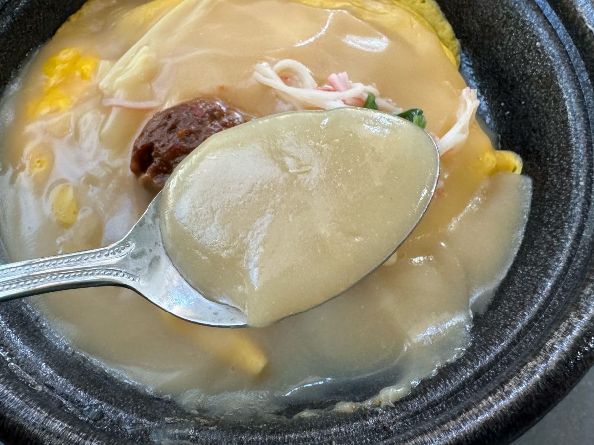 この溢れんばかりの濃厚こってりスープに、カニカマ・筍・特製肉味噌・ネギがトッピングされています