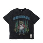 架空のストーリーをグラフィックに落とし込んだ、〈エグザンプル〉のTシャツ。こちらのTシャツはは、同ブランドで度々登場しているベア（熊）の、BB BEARをフィーチャー。森を彷徨うベアが、バーシティジャケットとデニムパンツを着用している。