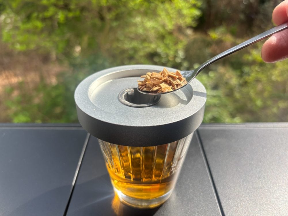 カクテルスモーカーをグラスに乗せ、燻製チップをスプーン1杯ほどセット