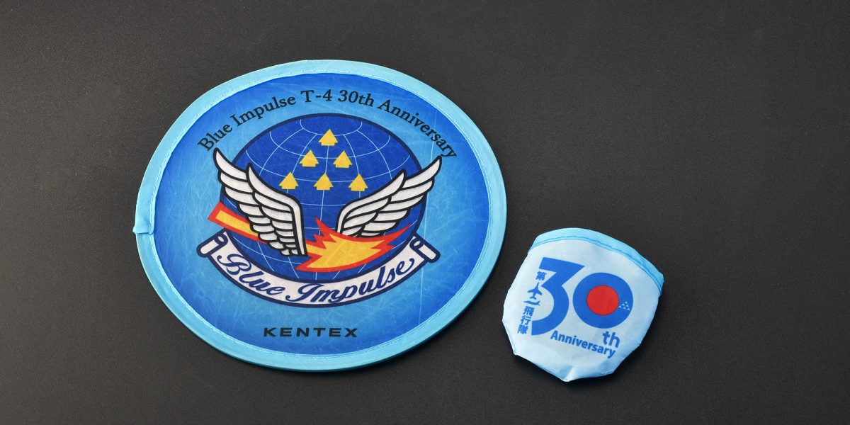 限定特典として、ブルーインパルス T-4 運用30周年記念ロゴをあしらったオリジナル折りたたみ式うちわ（非売品）を付属
