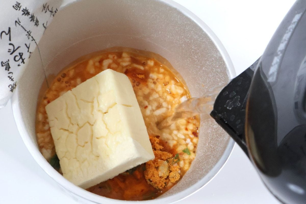 カップスープの中身を「めし粥」と一緒にしてお湯を注ぐ