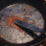 ヘラを使ってフライパンの焦げを削ぎ落とす