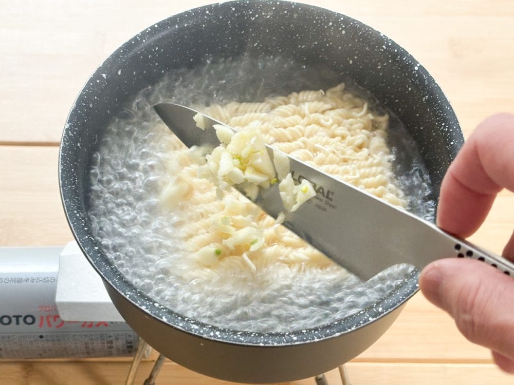 標準量より半分となる水、250mLが沸騰したらインスタント麺、刻んだニンニクを投入