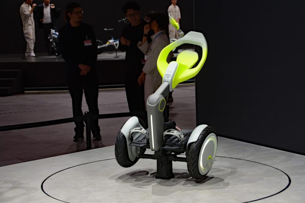 平行二輪のホイールの間にフットストッパーを搭載、上部のシートに座って体重移動によって動きを制御するトヨタの「BOOST ME」