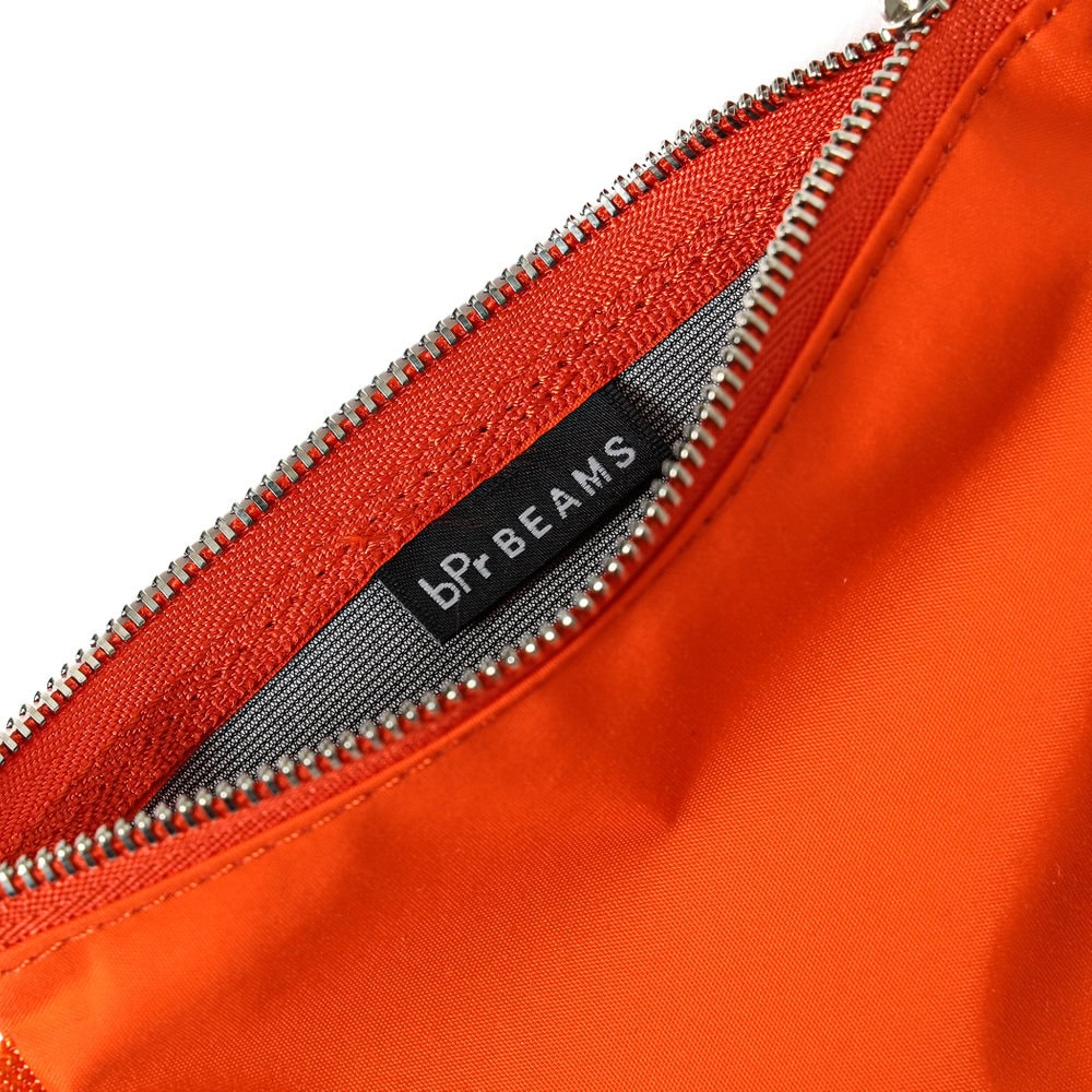 オレンジ色のバッグのジッパー部分とブランドタグ.