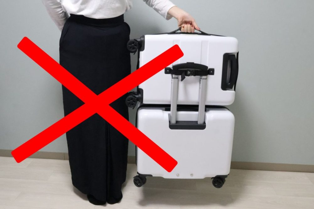 旅行用スーツケースと女性の手、赤いバツ印.