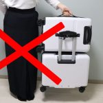 旅行用スーツケースと女性の手、赤いバツ印.