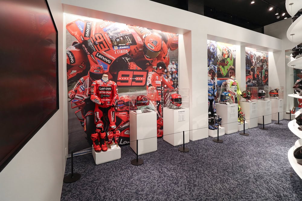 壁にはマルク・マルケス選手をはじめとする、SHOEIがサポートするMotoGPの現役ライダーやレジェンドライダーの本人用ヘルメット、レーシングスーツの展示が行われている