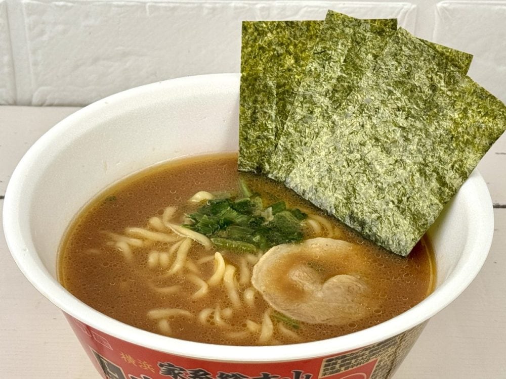 ローソン×明星食品 横浜家系総本山 吉村家 豚骨醤油ラーメン／スープは豚骨と鶏の旨みをベースに醤油だれを合わせ、さらに鶏油（チーユ）を効かせた家系らしいストロングなコクがありありの仕上がりです。粉末と液体のダブルスープ構成により、奥行きのある味わいを実現。具材はチャーシュー、ほうれん草、のり、ねぎと王道の組み合わせです