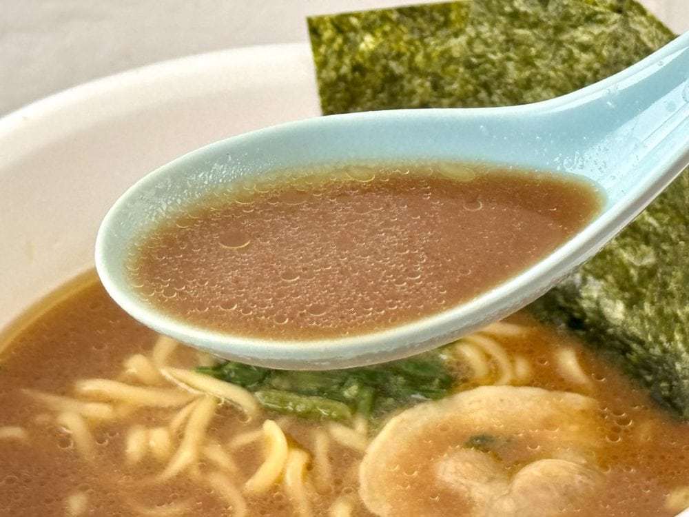 ローソン×明星食品 横浜家系総本山 吉村家 豚骨醤油ラーメン／実食してみると、スープを一口すすった瞬間に「あ、家系だ！」という感動があります。豚骨の旨みが確実に先に飛び込んでくる後に醤油のキレと香りが口内にガツンとくる