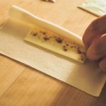 端にトッポを置いてきつめに巻き、小麦粉を水で溶いたのりで閉じる