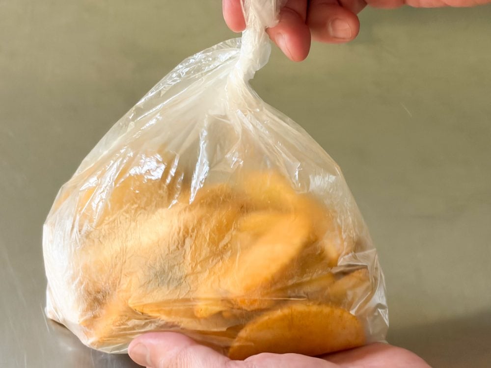 「フライドポテトナチュラルウェッジ」をビニール袋に入れ、タコス用のシーズニングを加え、よく絡ませます